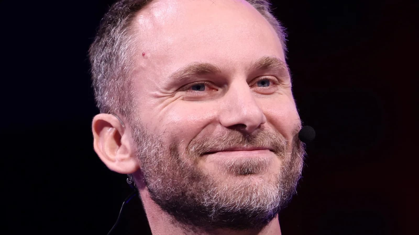 Paolo Ardoino, CEO von Tether, lächelnd und mit Headset-Mikrofon bei einem Bühnenauftritt in Las Vegas, vor dunklem Hintergrund